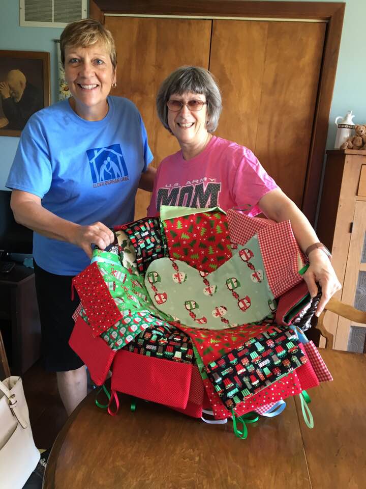 Kim Jackson and Karen Wingate hold a basket of the Christmas Stockings of Joy