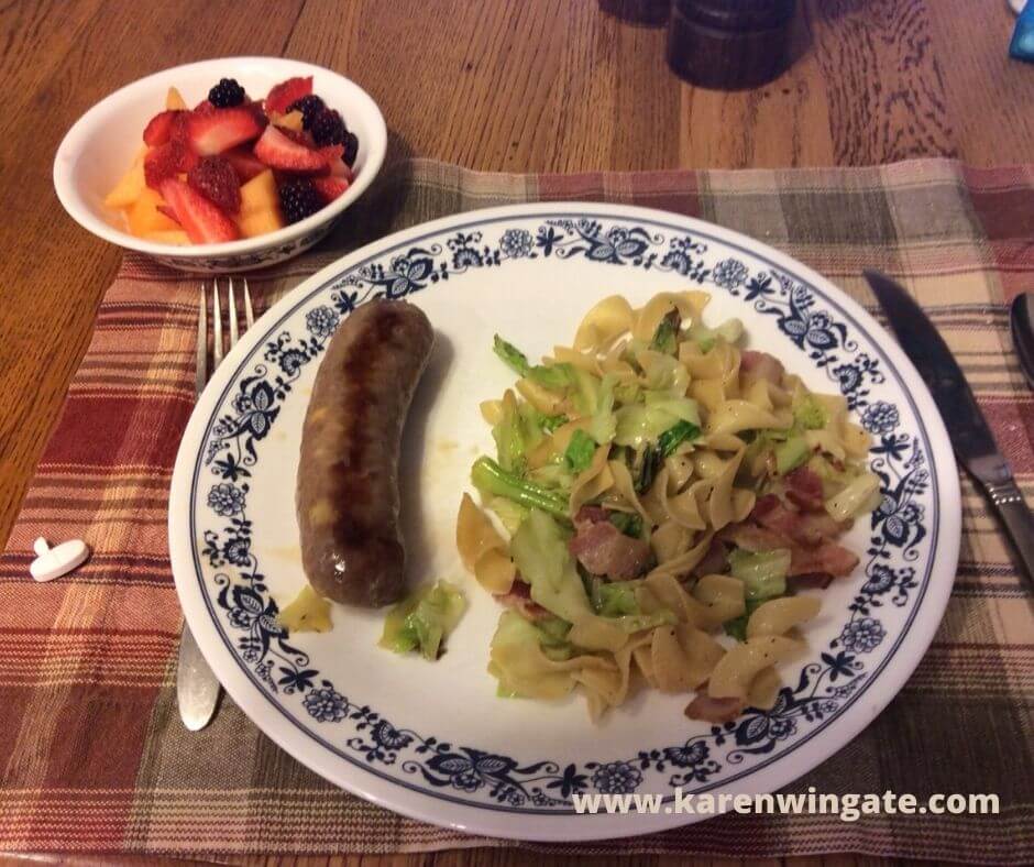 Fried cabbage and noodles dinner with polish kielbasa and fruit medley